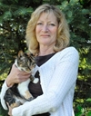Bio photo of Dr. Claudia J. Baldwin in an outdoor setting, smiling and holding a brown and white cat